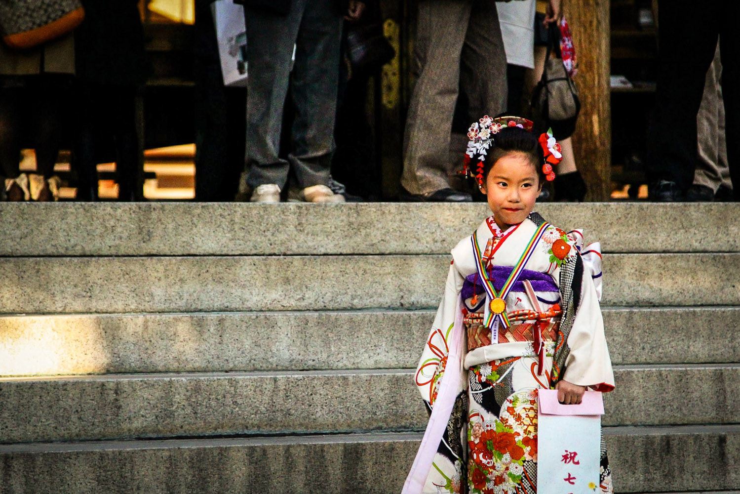 Young girl in a kimono stands on the main steps of a Shinto shrine, Tokyo
