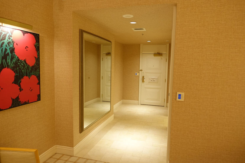 The marble foyer was flanked by a huge mirror on one side and the bathroom door on the other.