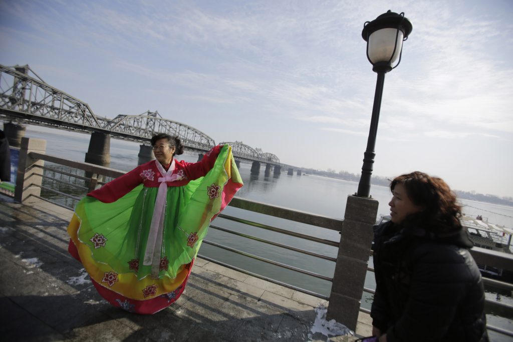 A tourist wears a traditional Korean dress to have a souvenir photo taken. Pic: AP