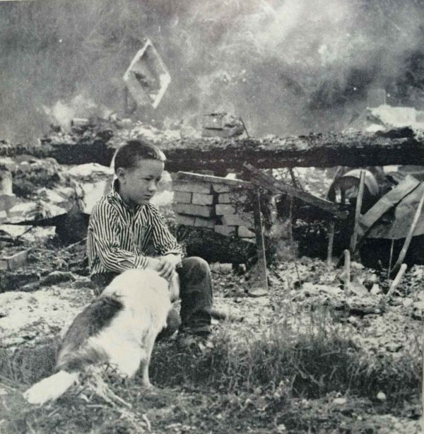 Sons of Freedom boy sits near the ashes of his burned home, 1962. Photo by George Diack