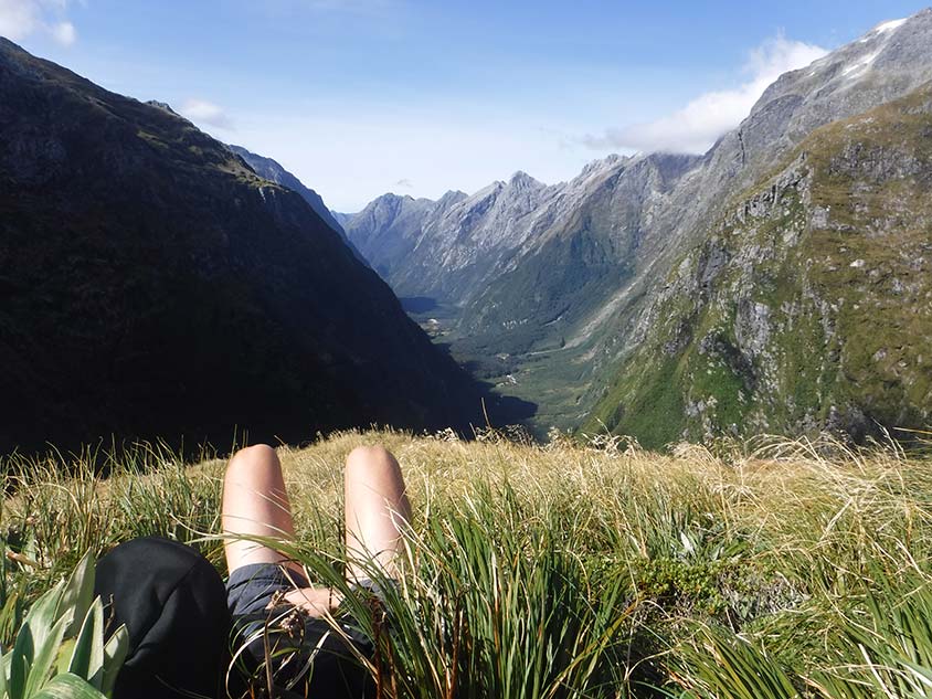 A person lays back above a glacial valley enjoying the view.