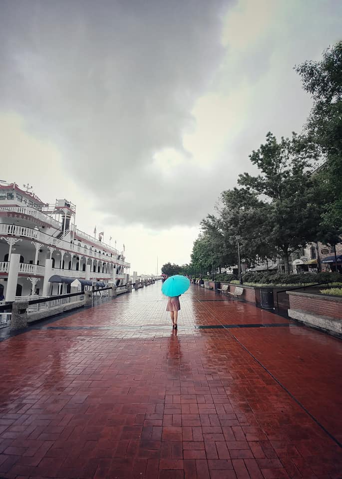 Kelsey walking along River Street in the rain in Savannah, Georgia