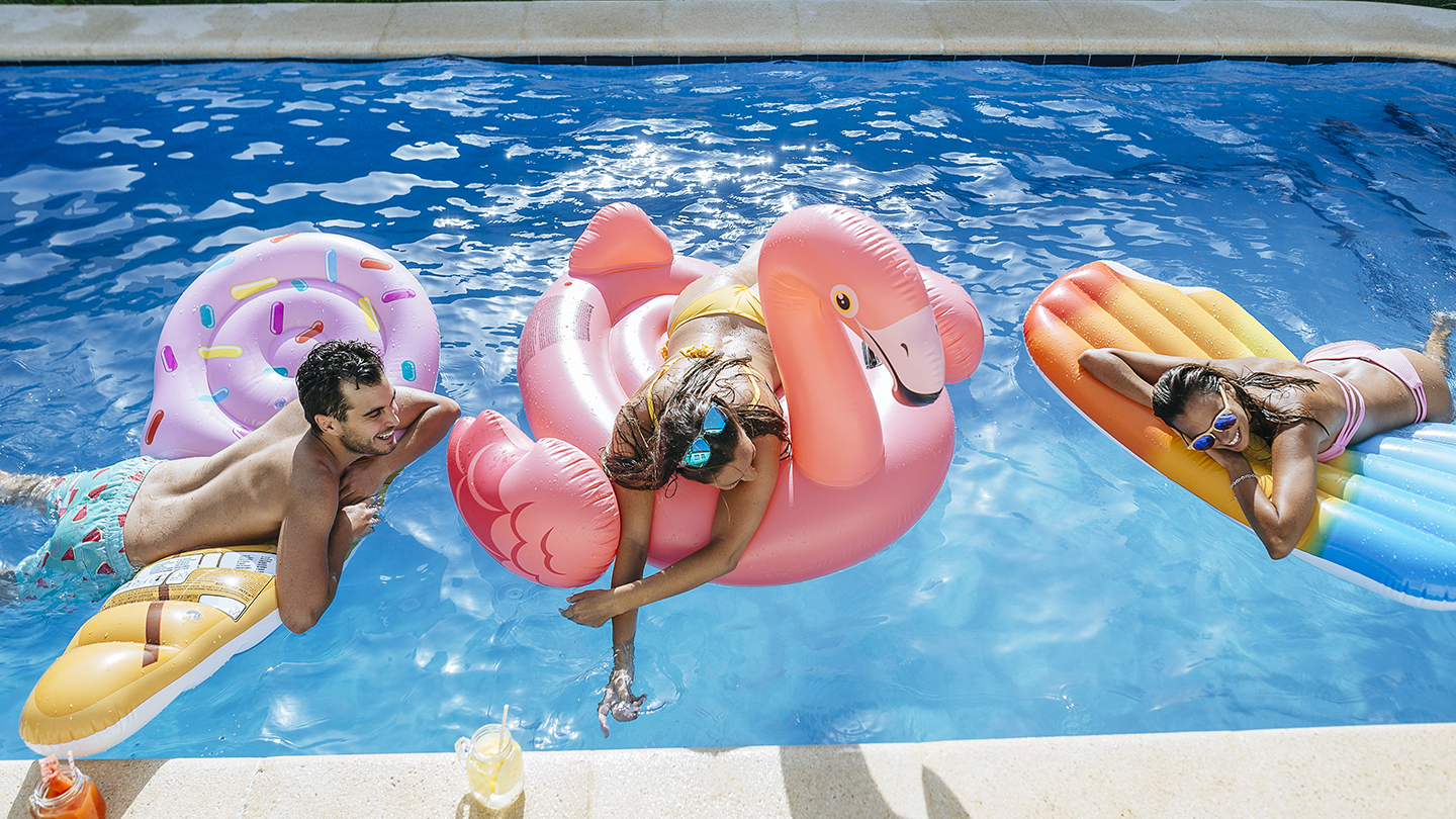 Spain, Andalusia, cadiz, El Puerto de Santa Maria, Friends in pool mounted on ice cream and flamingo floats.