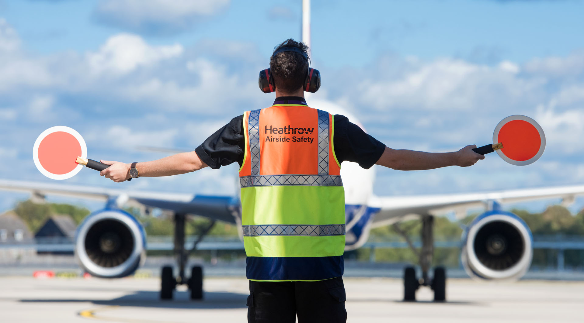 Heathrow, airfield, airfield ops marshaller guiding aircraft on apron, Sep 2018.